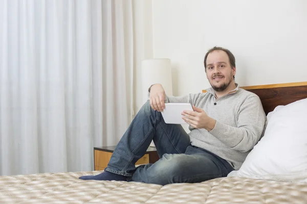 Homem casual trabalhando com um tablet pc na cama — Fotografia de Stock