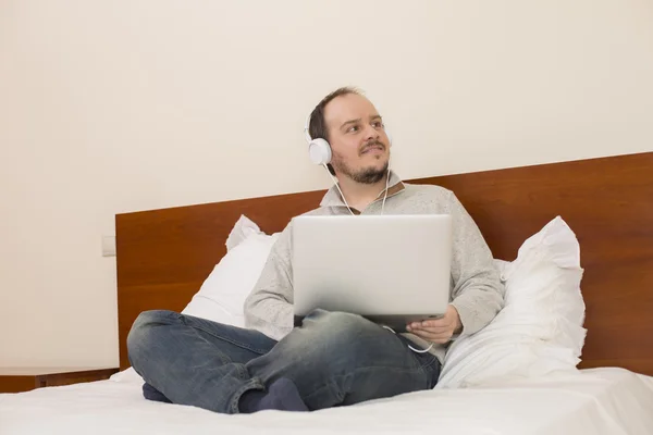 Mann im Bett arbeitet mit Laptop — Stockfoto