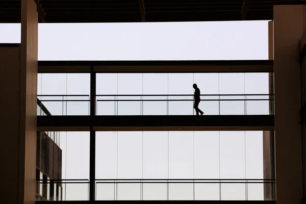 Vista de la silueta del joven empresario en un moderno edificio de oficinas interior —  Fotos de Stock