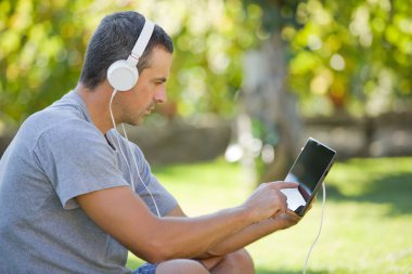 genç adam bir kulaklık ile müzik dinleme tablet pc ile rahatlatıcı
