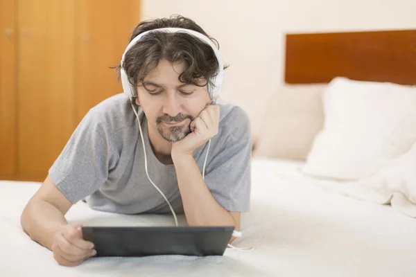 Uomo casuale che lavora con un tablet pc a letto — Foto Stock