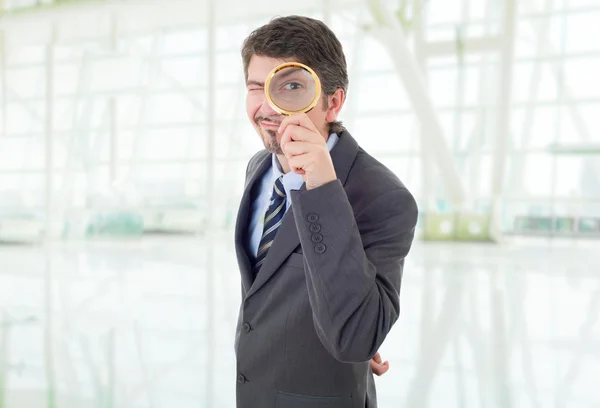 Junger Geschäftsmann mit Lupe im Büro — Stockfoto