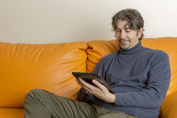 Случайный человек, работающий с планшетным компьютером на диване, дома — стоковое фото