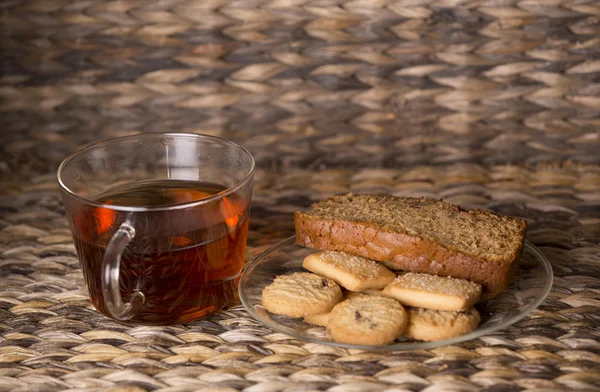 Thé, biscuits et gâteau sur une table en bois devant un fond en bois — Photo