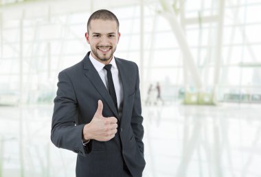 Genç iş adamı ofiste başparmağını kaldırıyor.