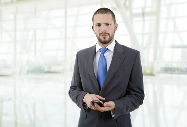 Junger Geschäftsmann schaut auf sein Telefon, im Büro — Stockfoto