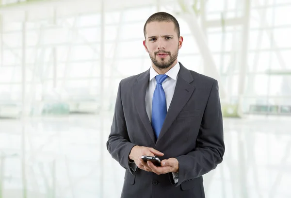 Ung affärsman tittar på sin telefon, på kontoret — Stockfoto