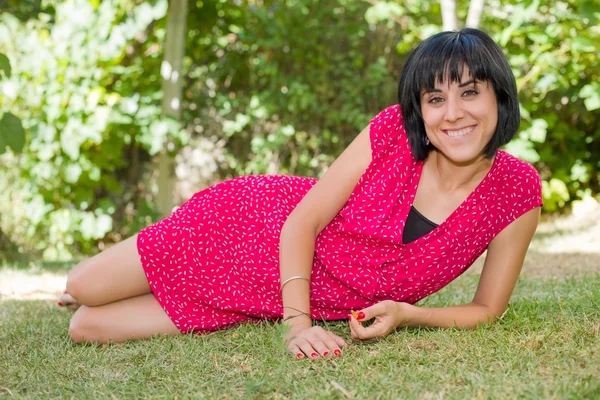 Fiatal alkalmi nő pózol ül, mosolyogva a kamerába, szabadban — Stock Fotó