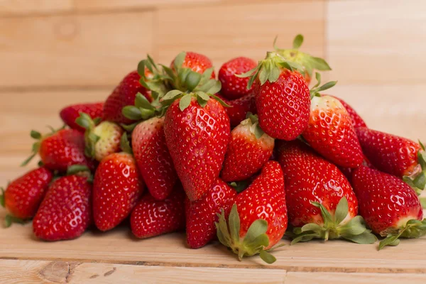 Strawberries on wooden table in front of a wooden background — Stock Photo, Image