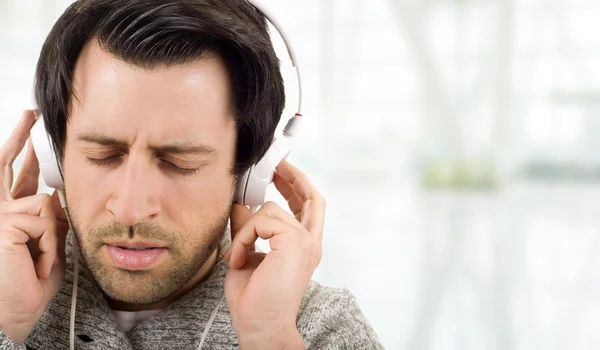 Jeune homme heureux avec écouteurs, écoutant de la musique les yeux fermés — Photo