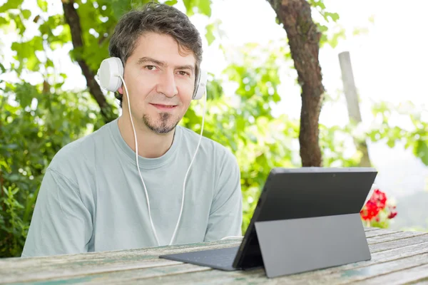 Człowiek relaksujący z tablet pc słuchania muzyki ze słuchawkami — Zdjęcie stockowe
