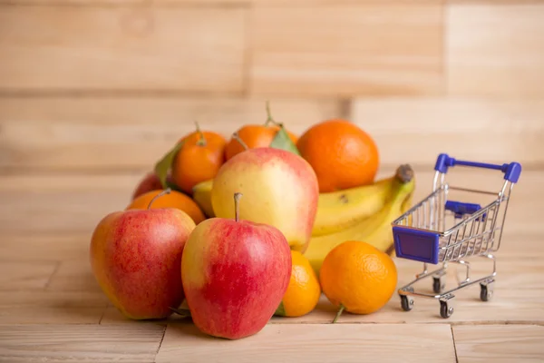 Frukt och en kundvagn på ett träbord, studio bild — Stockfoto