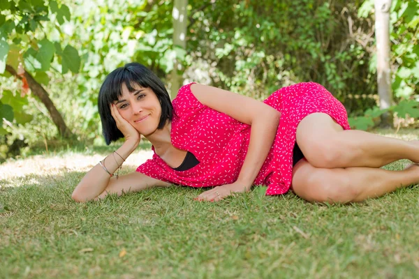 Ung casual kvinna poserar sittande, ler mot kameran, utomhus — Stockfoto
