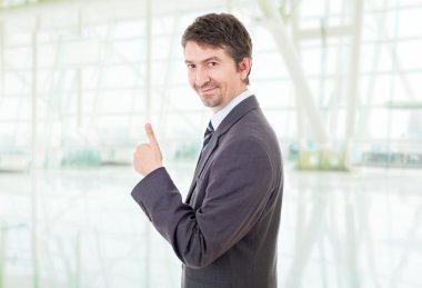 Genç iş adamı ofiste başparmağını kaldırıyor.