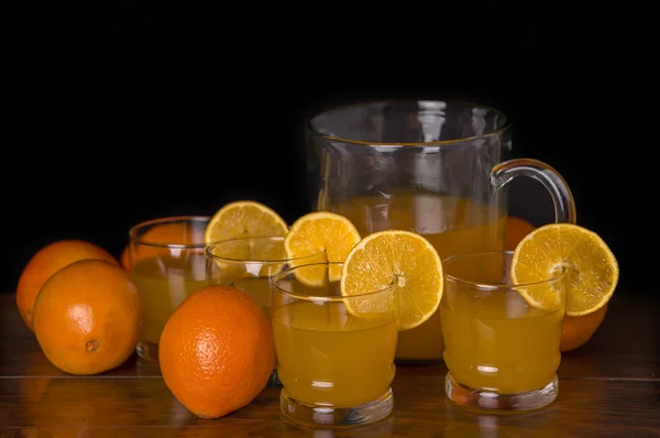 Verre de jus d'orange délicieux avec des oranges sur une table, photo de studio — Photo