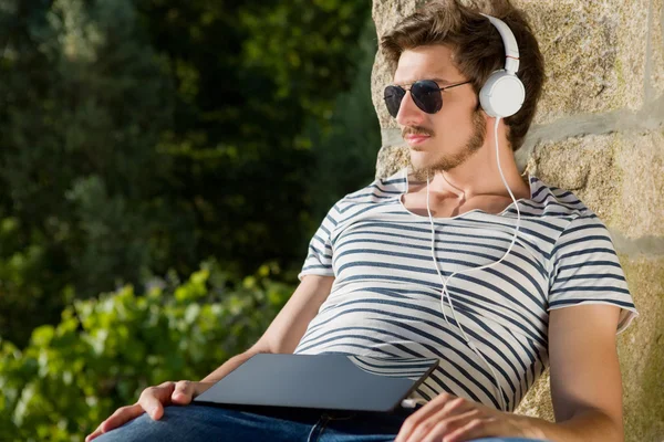 Młody człowiek relaksujący z tabliczka pc słuchania muzyki w słuchawkach — Zdjęcie stockowe