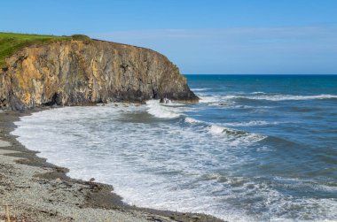Rocky Rugged Plajı 'nda güneşli bir gün Bakır Sahili, İrlanda' da okyanusa bakıyor.