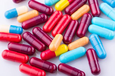 Haplar, kapsül yığını, karışık terapi ilaçları, beyaz bir arka plan.