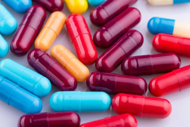 Haplar, kapsül yığını, karışık terapi ilaçları, beyaz bir arka plan.