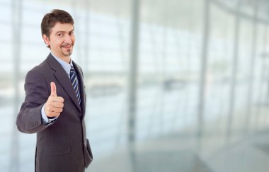 Genç iş adamı ofiste başparmağını kaldırıyor.