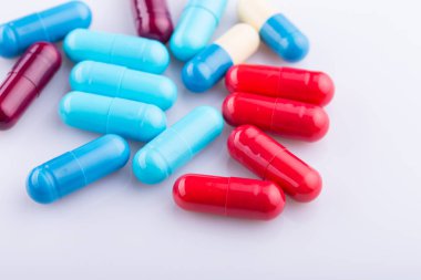 Haplar, kapsül yığını, karışık terapi ilaçları, beyaz bir arka plan.