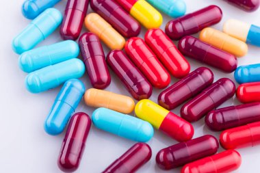 Haplar, kapsül yığını, karışık terapi ilaçları, beyaz bir arka plan.