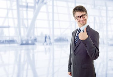 Genç iş adamı ofiste başparmağını kaldırıyor.