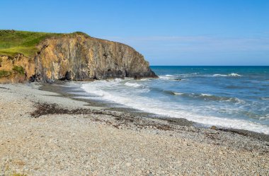 Rocky Rugged Plajı 'nda güneşli bir gün Bakır Sahili, İrlanda' da okyanusa bakıyor.