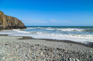 Rocky Rugged Plajı 'nda güneşli bir gün Bakır Sahili, İrlanda' da okyanusa bakıyor.