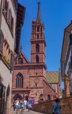 Basel, İsviçre: İnsanlar kırmızı kumtaşı Basler Munster 'a (Munster Katedrali) doğru bir kaldırım taşı caddesinde yürüyor)