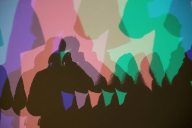 Renkli gölgeler, RGB aydınlatması boyunca duvara vurularak soyut ve sanatsal bir etkileşim yaratıyor insan siluetleri ve üst üste binen ışık.