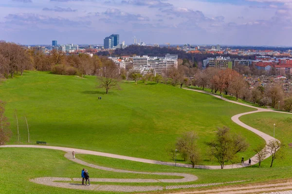 Münih, Almanya: Münih 'teki Olympia parkında yeşil çimenler, ağaçlar ve insanlar var. 1972 Yaz Olimpiyatları için inşa edildi.