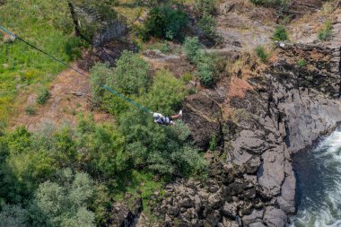 Melgaco, Portekiz: Portekiz 'in kuzeyinde kayalarla çevrili Minho Nehri üzerindeki kayalık bir uçurumdan atlayan bungee jumper.
