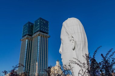 Madrid, Spain: Modern architecture and a giant head sculpture under clear blue skies in Madrids Plaza de Coln.