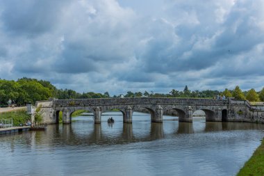 Chambord, Fransa: Bot ve ziyaretçilerle birlikte Chambord Şatosu bahçelerindeki sakin nehrin üzerindeki taş kemer köprüsü