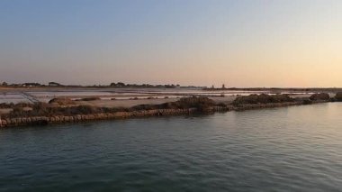 İtalya 'nın Trapani kenti yakınlarındaki sakin tuzlu tavaların üzerinde altın gün batımı