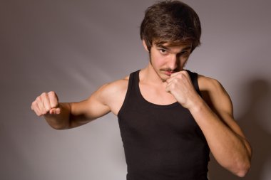 Yakışıklı bir genç adam yumruklarını gösterilen Studio portresi