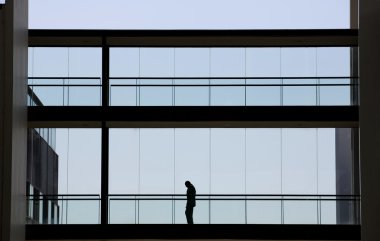 Genç işadamı modern ofis panoramik pencerelere sahip iç Binası yürüme görünümünü siluet.