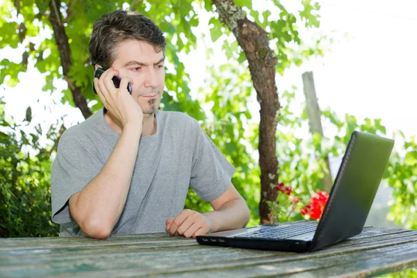 Человек сидит на открытом воздухе, работает с ноутбуком — стоковое фото