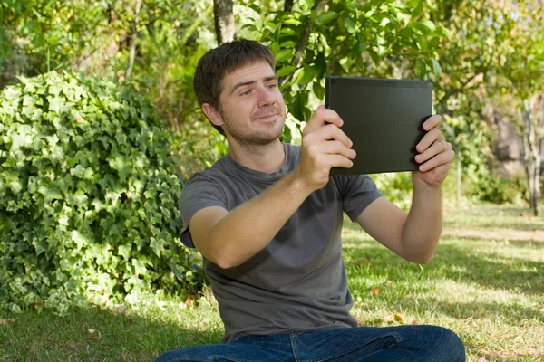 Случайный человек, фотографирующийся с планшетным компьютером, на открытом воздухе — стоковое фото