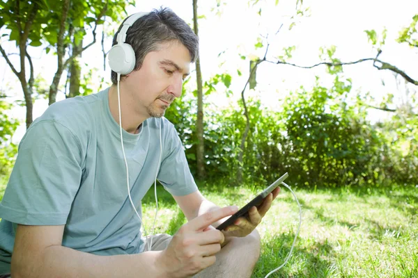 Young man holding a tablet with headphones, outdoor — Stock Photo, Image