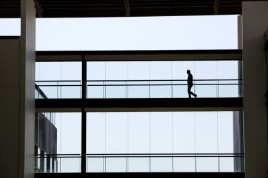 Modern ofis binasında panoramik pencereli genç bir işadamının silüeti..