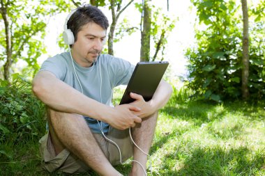 genç adam bir tablet ile kulaklıklar, açık tutarak