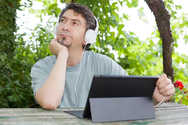 Genç adam bir tablet ile kulaklıklar, açık tutarak — Stok fotoğraf