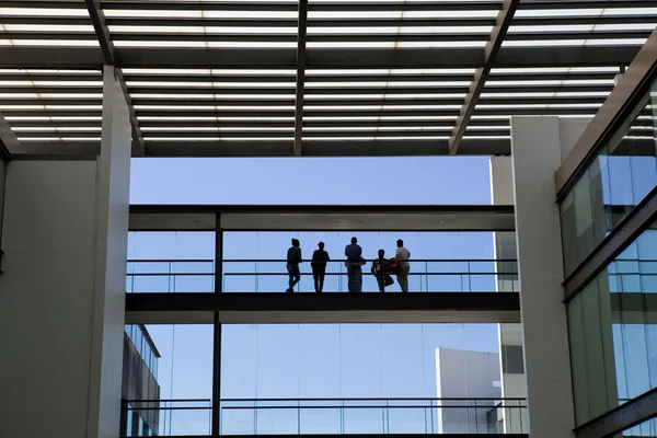 Silhouette view of some people in a modern office building interior with panoramic windows. — Stock Photo, Image