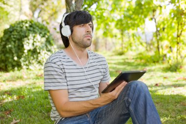 genç adam bir tablet ile kulaklıklar, açık tutarak
