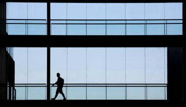 Genç işadamı modern ofis binası içinde yürüyüş görünümünü siluet