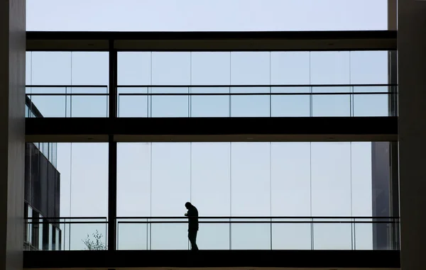 Siluett bild av ung affärsman promenader i modern kontorsbyggnad inredning — Stockfoto