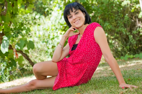 Young casual woman posing seated, smiling at the camera, outdoors — Stock Photo, Image