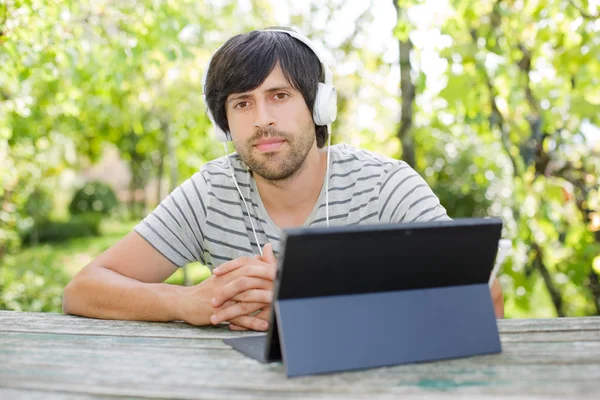 Junger Mann mit Tablet und Kopfhörer, im Freien — Stockfoto